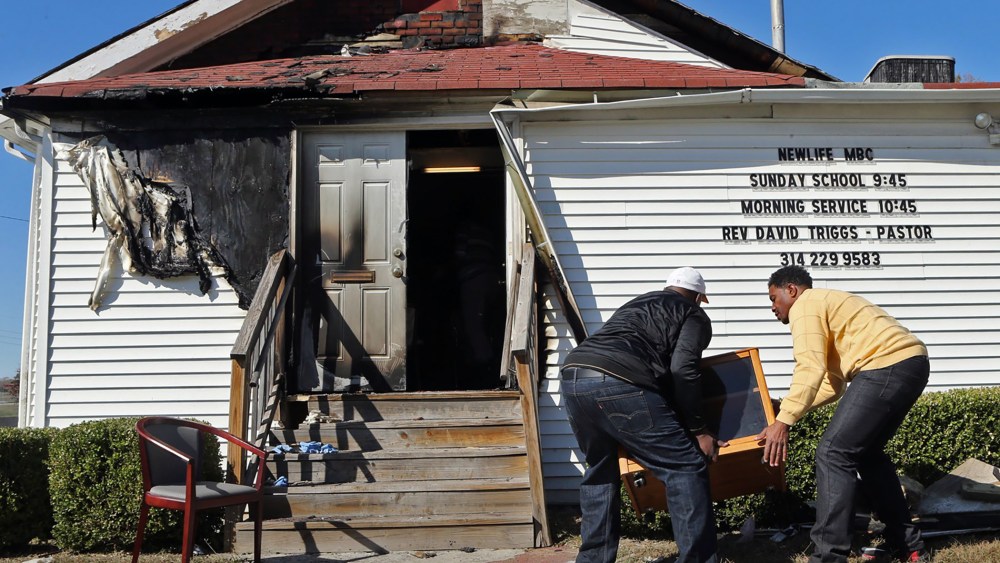 In this Sunday, Oct. 18, 2015 photo, Deacon Clinton McMiller and Pastor David Triggs carry a cabinet after an outdoor service due to a fire at the New Life Missionary Baptist Church in St. Louis. (Photo by J.B. Forbes/St. Louis Post-Dispatch/AP)