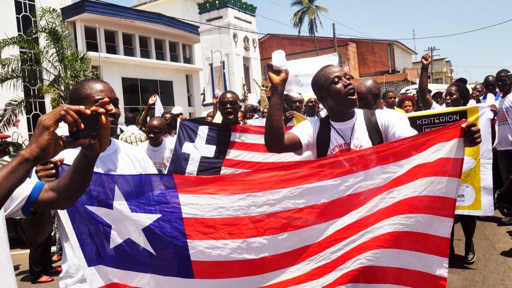 People march with a Liberian flag as they celebrate Liberia being an Ebola free nation in Monrovia, Liberia, Monday, May 11, 2015. (Photo by Abbas Dulleh/AP)