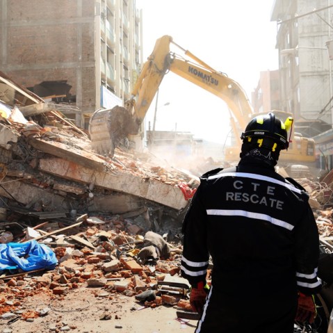 A rescue worker looks as heavy machinery removes the debris of a collapsed building in Portoviejo, Ecuador, April 17, 2016. (Photo by Carlos Sacoto/AP)