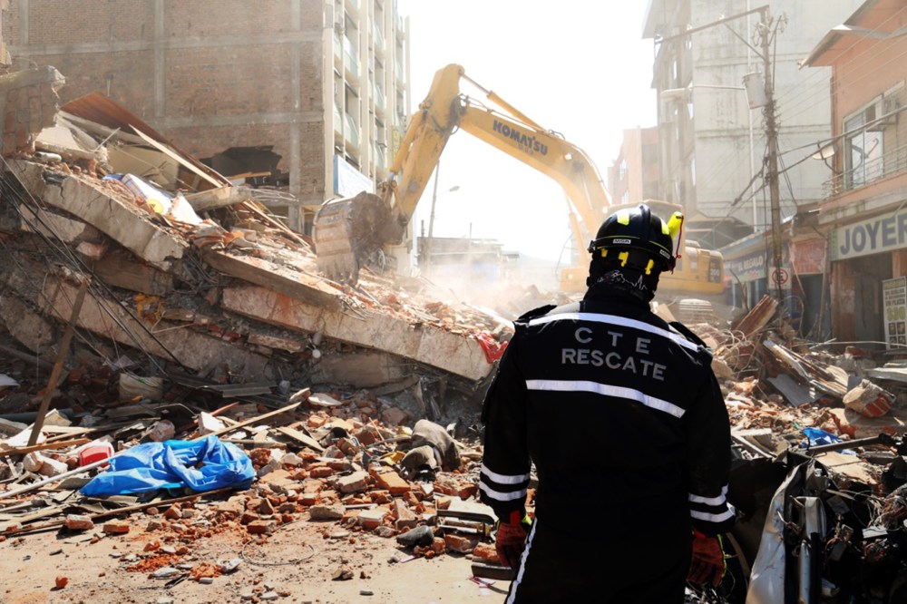 A rescue worker looks as heavy machinery removes the debris of a collapsed building in Portoviejo, Ecuador, April 17, 2016. (Photo by Carlos Sacoto/AP)