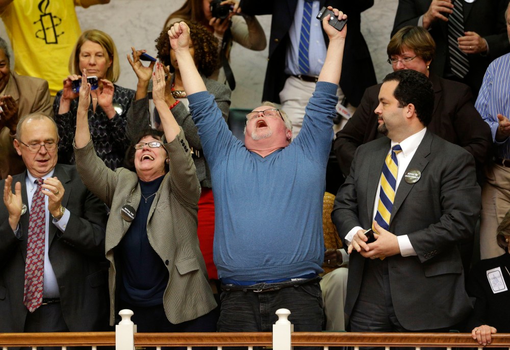 Anti-death penalty advocates Sylvester Schieber, left, his wife, Vicki, center, Kirk Bloodsworth, the first American sentenced to death row who was exonerated by DNA, and NAACP President Ben Jealous, right, react after watching the Maryland General...