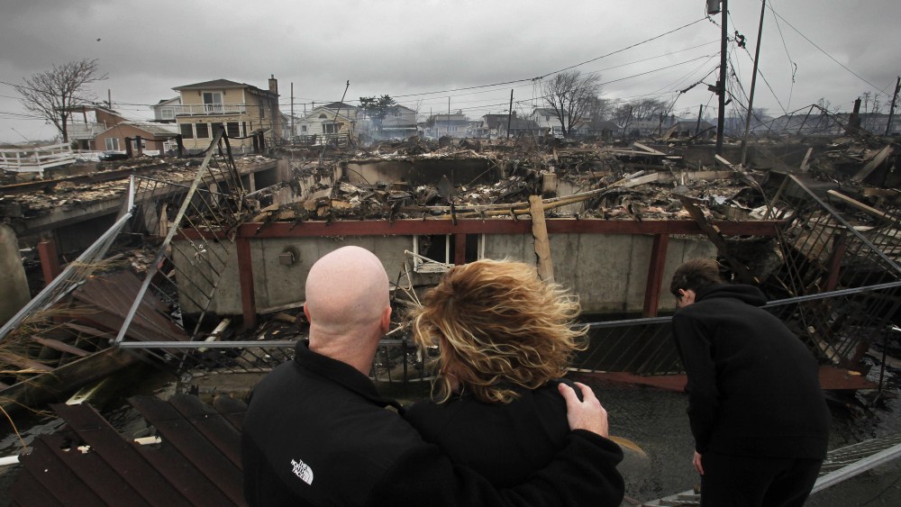 Robert Connolly, left, embraces his wife Laura as they survey the remains of the home owned by her parents that burned to the ground in the Breezy Point section of New York, Tuesday, Oct. 30, 2012. More than 50 homes were destroyed in the fire which...