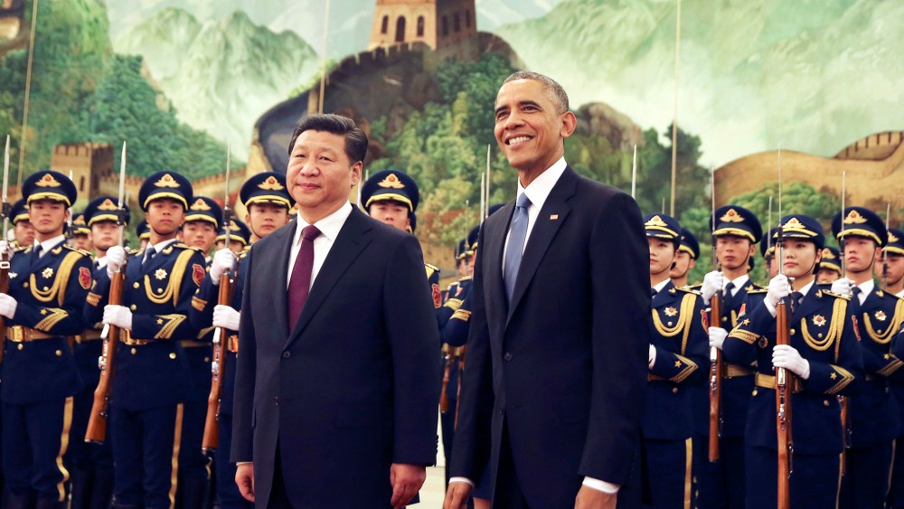 U.S. President Barack Obama, right, smiles after a group of children waved flags and flowers to cheer him during a welcome ceremony with Chinese President Xi Jinping at the Great Hall of the People in Beijing, China, Nov. 12, 2014. (Photo by Andy Wong/AP)
