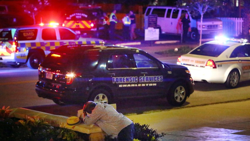 A man kneels across the street from where police gather outside the Emanuel AME Church following a shooting, June 17, 2015, in Charleston, S.C. (Photo by Wade Spees/The Post And Courier/AP)