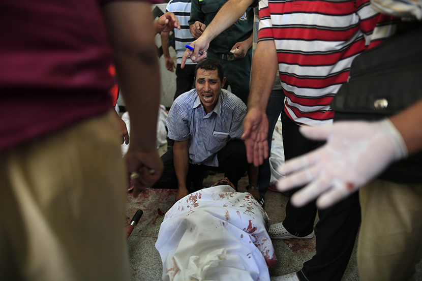 An Egyptian man sits beside his comrade, a supporter of Egypt's ousted President Mohammed Morsi, injured during clashes with security forces at Nasr City, where pro-Morsi protesters have held a weeks-long sit-in, in a field hospital in Cairo, Egypt,...