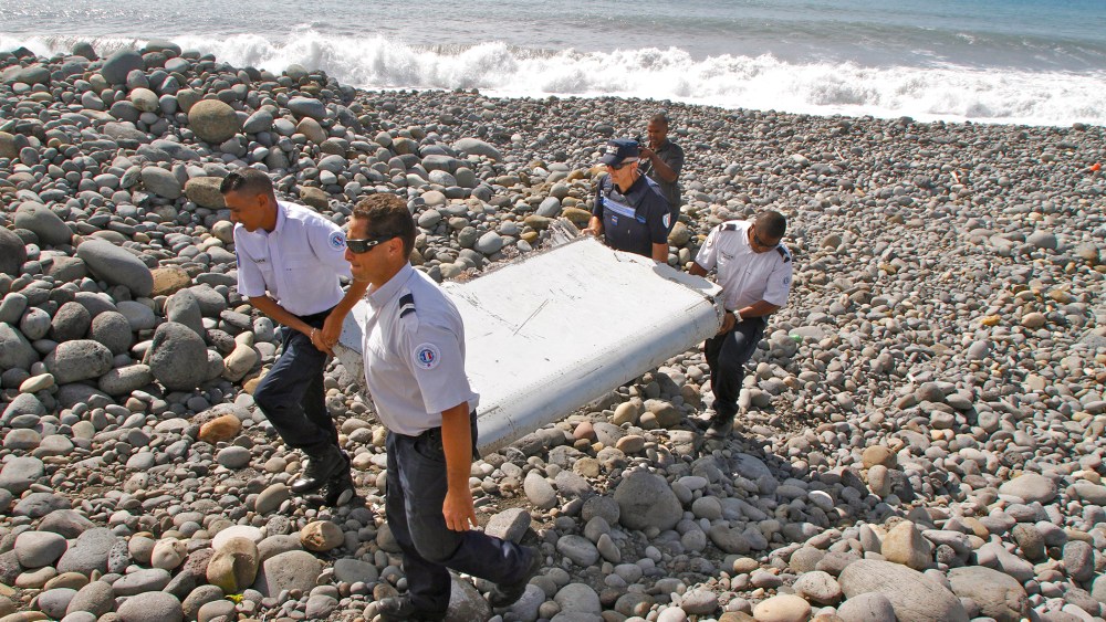 In this photo dated July 29, 2015, French police officers carry a piece of debris from a plane in Saint-Andre, Reunion Island. (Photo by Lucas Marie/AP)