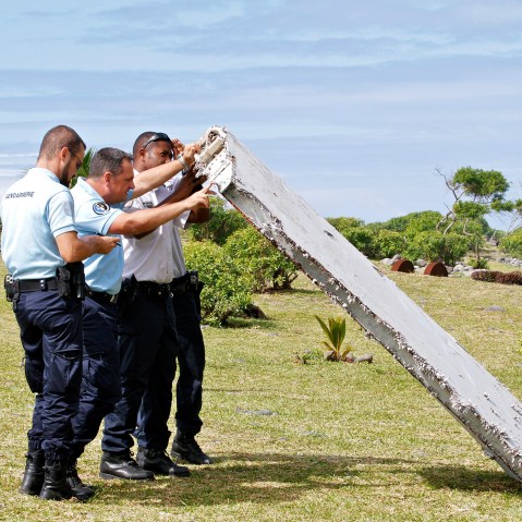 In this photo dated July 29, 2015, French police officers inspect a piece of debris from a plane in Saint-Andre, Reunion Island. (Photo by Lucas Marie/AP)
