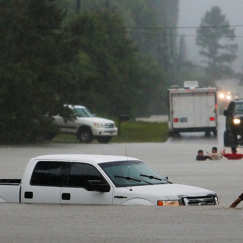 Three men, pictured in the background, lost control of their truck after they drove around a closed road barrier along Nichols Sawmill Road in rising flood water, May 27, 2016 in Magnolia, Texas. (Photo by Michael Ciaglo/Houston Chronicle/AP)