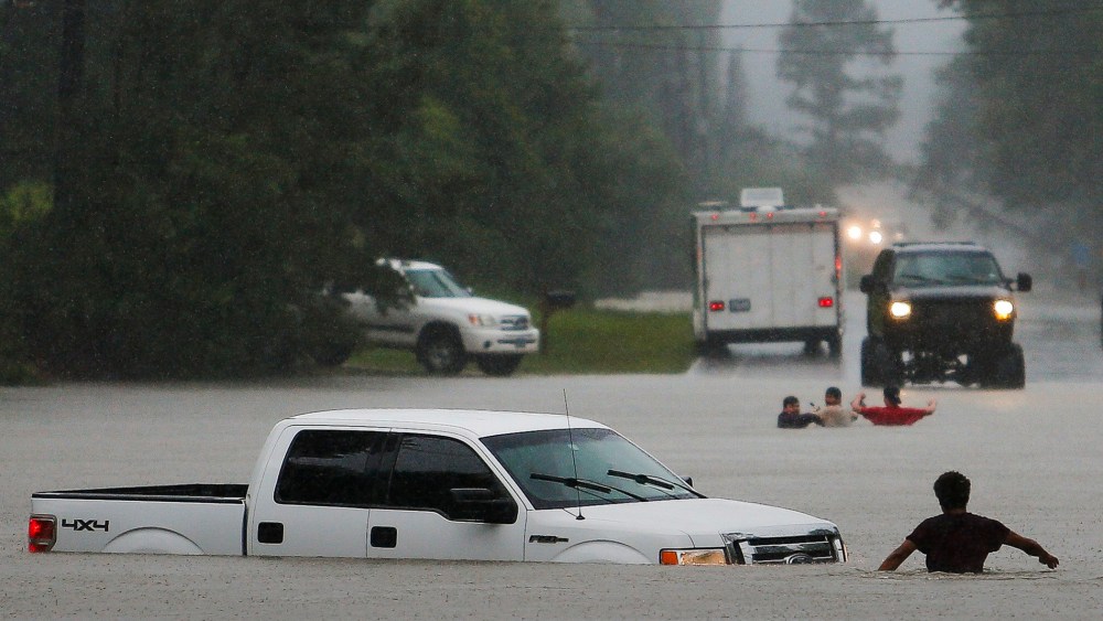 Three men, pictured in the background, lost control of their truck after they drove around a closed road barrier along Nichols Sawmill Road in rising flood water, May 27, 2016 in Magnolia, Texas. (Photo by Michael Ciaglo/Houston Chronicle/AP)