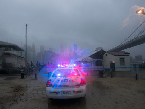 A police car patrols the Brooklyn waterfront as storm clouds blow over the Manhattan skyline in New York (Keith Bedford/Reuters)