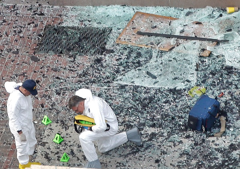 Two men in hazardous materials suits put numbers on the shattered glass and debris as they investigate the scene at the first bombing on Boylston Street in Boston Tuesday, April 16, 2013 near the finish line of the 2013 Boston Marathon, a day after two...