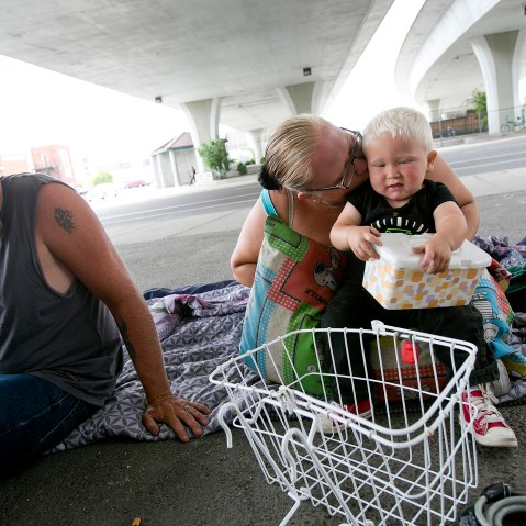 Tealla Dilka, with her husband Will at left, plays with her 18-month-old son David as they lay on the asphalt underneath the 16th Street bridge in Boise, Idaho on June 25, 2014.