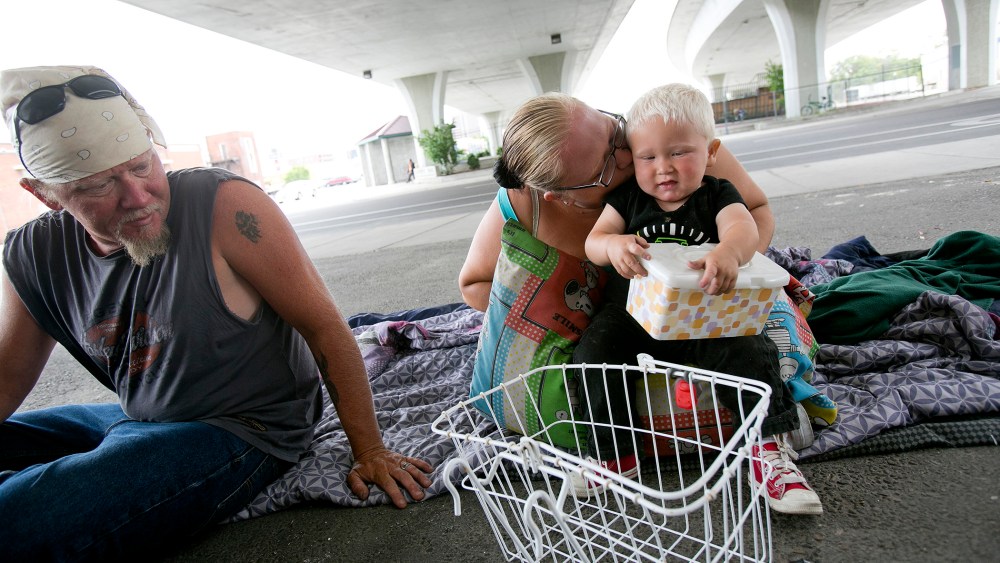 Tealla Dilka, with her husband Will at left, plays with her 18-month-old son David as they lay on the asphalt underneath the 16th Street bridge in Boise, Idaho on June 25, 2014.