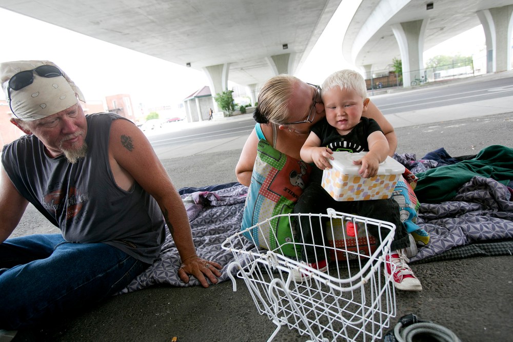 Tealla Dilka, with her husband Will at left, plays with her 18-month-old son David as they lay on the asphalt underneath the 16th Street bridge in Boise, Idaho on June 25, 2014.