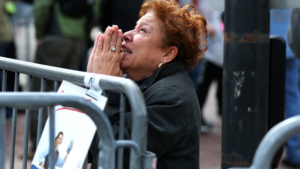 BOSTON - APRIL 15: A woman kneels and prays at the scene of the first explosion on Boylston Street near the finish line of the 117th Boston Marathon on April 15, 2013. (Photo by John Tlumacki/The Boston Globe via Getty Images)