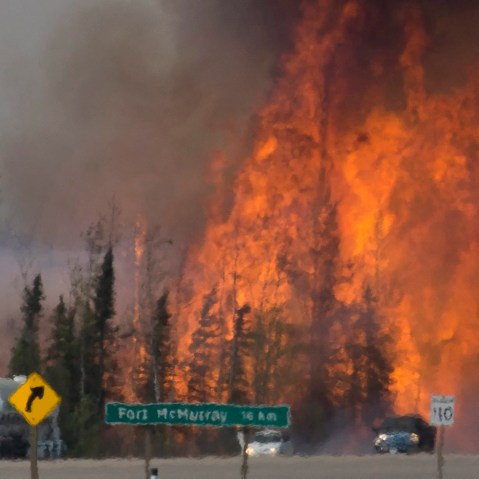 Heat waves are seen as cars and trucks try and get past a wild fire 16 km south of Fort McMurray, Alberta, on highway 63, May 6, 2016. (Photo by Jonathan Hayward/The Canadian Press/AP)