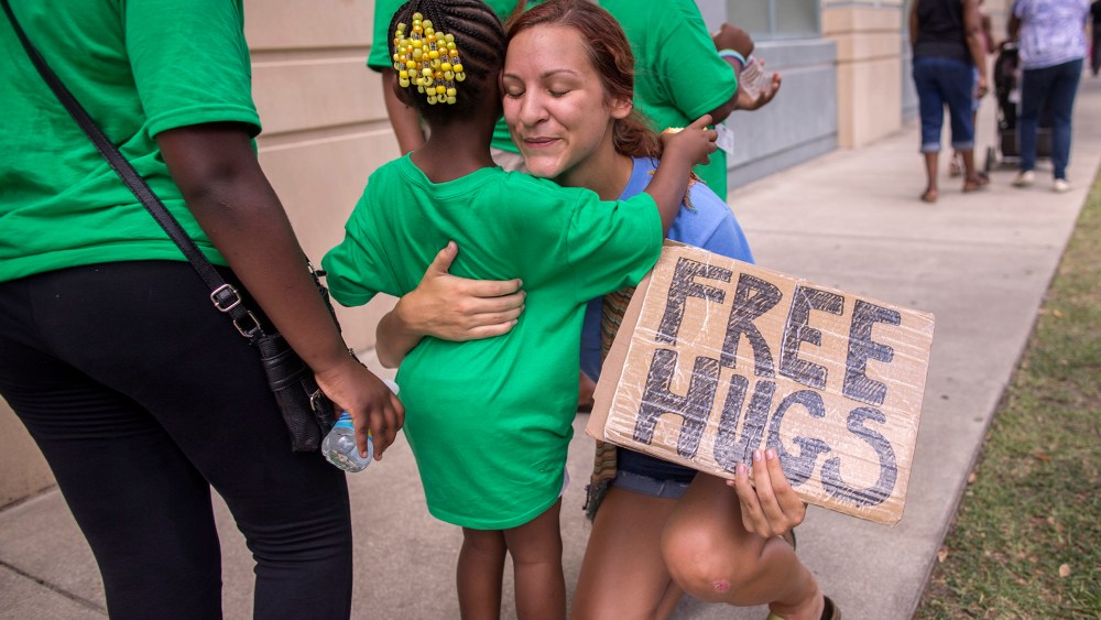 Sharry Schuller of Charleston give out free hugs to anyone who wants one while visiting the memorial in front of the Emanuel AME Church, June 20, 2015, in Charleston, S.C. (Photo by Stephen B. Morton/AP)