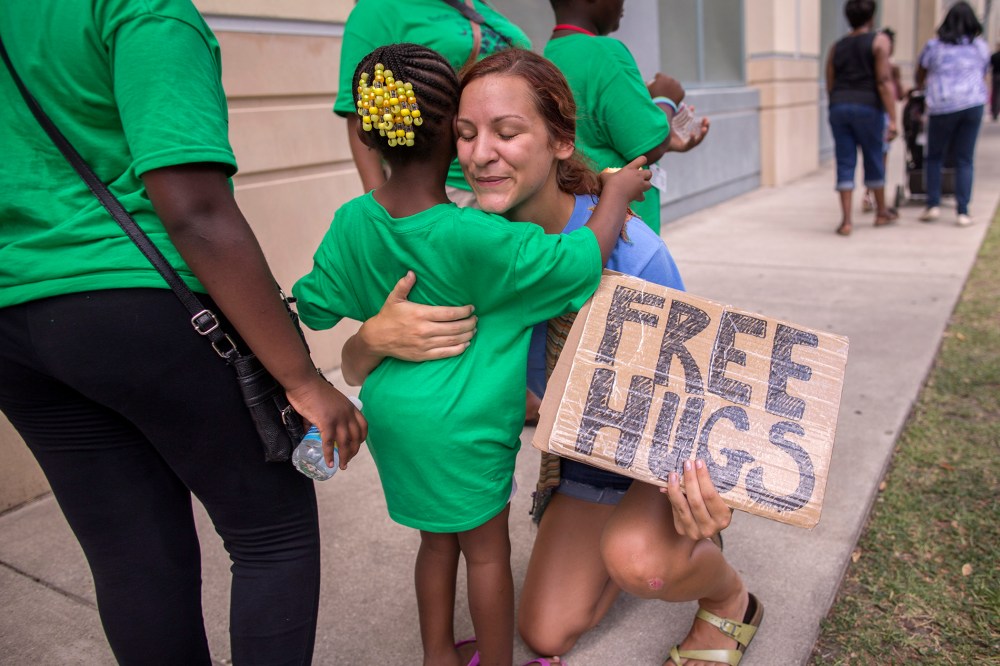 Sharry Schuller of Charleston give out free hugs to anyone who wants one while visiting the memorial in front of the Emanuel AME Church, June 20, 2015, in Charleston, S.C. (Photo by Stephen B. Morton/AP)