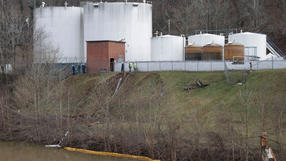 Workers inspect an area outside a retaining wall around storage tanks where a chemical leaked into the Elk River at Freedom Industries storage facility  in Charleston, West Virginia, Monday, Jan. 13, 2014.