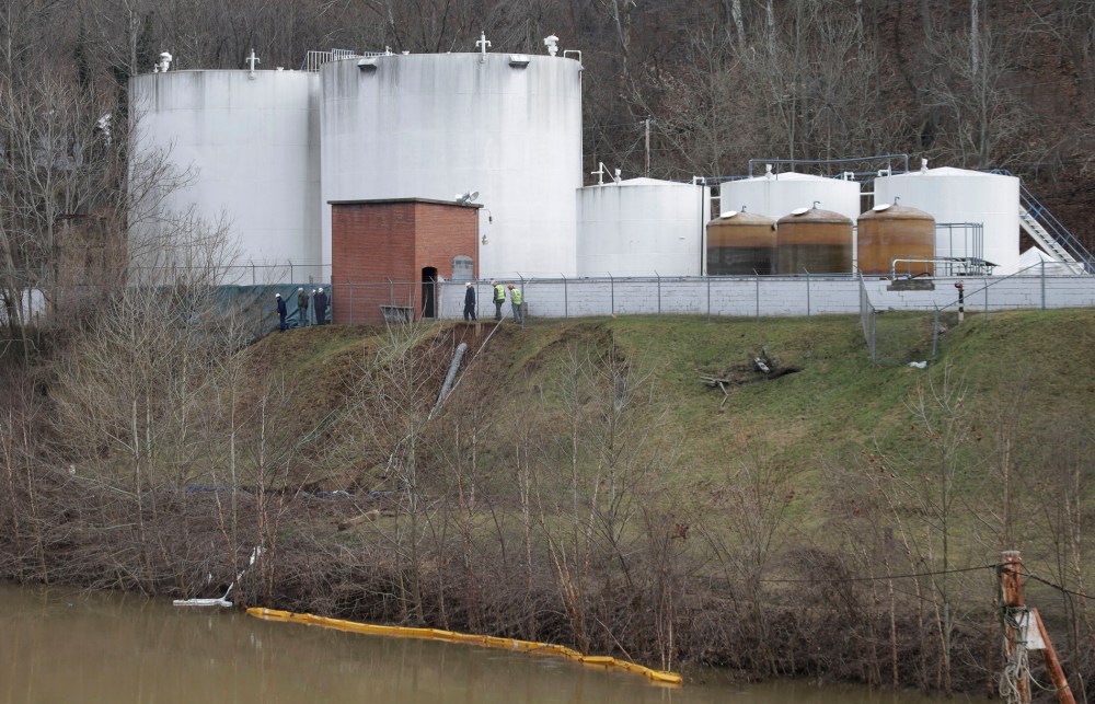 Workers inspect an area outside a retaining wall around storage tanks where a chemical leaked into the Elk River at Freedom Industries storage facility  in Charleston, West Virginia, Monday, Jan. 13, 2014.