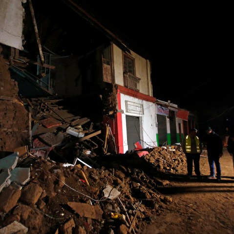 People stand outside a destroyed house in Illapel, Chile, Sept. 17, 2015. (Photo by Luis Hidalgo/AP)