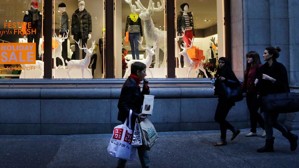 In this Friday, Nov. 22, 2013 photo, shoppers walk past windows at a Joe Fresh clothing store in New York.