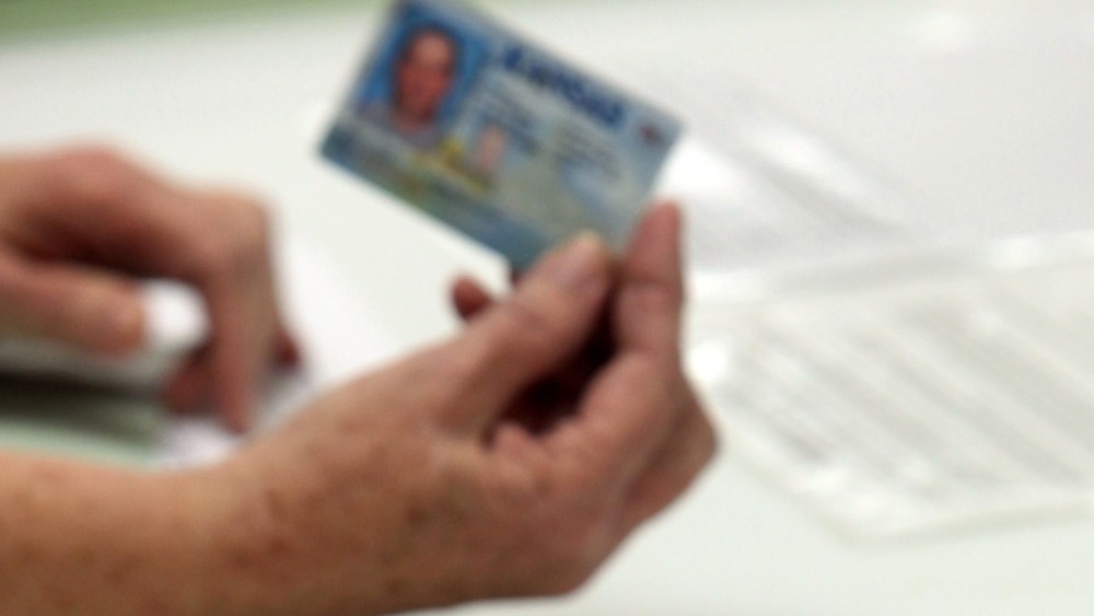FILE - In this Jan. 10, 2012 file photo, election officials check the photo identification card of a voter in Cimarron, Kan. Voter ID laws designed to deter fraud may end up blocking thousands of legitimate ballots.  (AP Photo/The The Hutchinson News,...