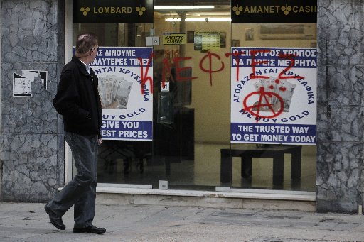 A man passes a sprayed entrance of a store that buys gold which reads in Greek "thieves" in capital Nicosia, Cyprus, Monday, March 25, 2013. (AP Photo/Petros Giannakouris)