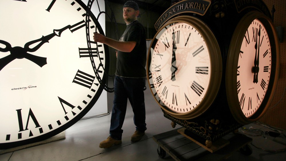 In this Thursday, Nov. 3, 2011 photo, Dan LaMoore of Electric Time Company moves a clock face at their plant in Medfield, Mass.