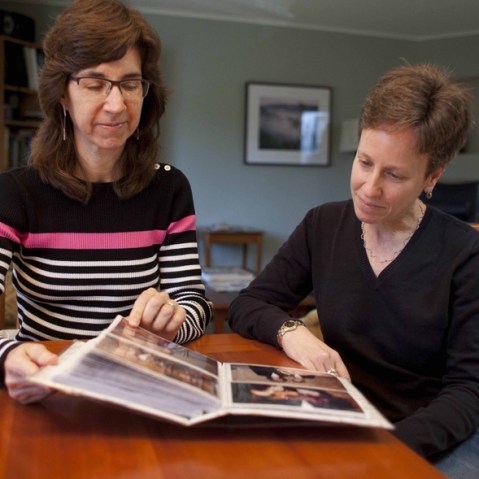 In this photo taken Nov. 12, 2012, Karen Golinski (left) and Amy Cunninghis look over a photo album of their wedding photos in San Francisco. Golinski wanted to enroll her spouse in her employer-sponsored health plan. Four years later, her request...