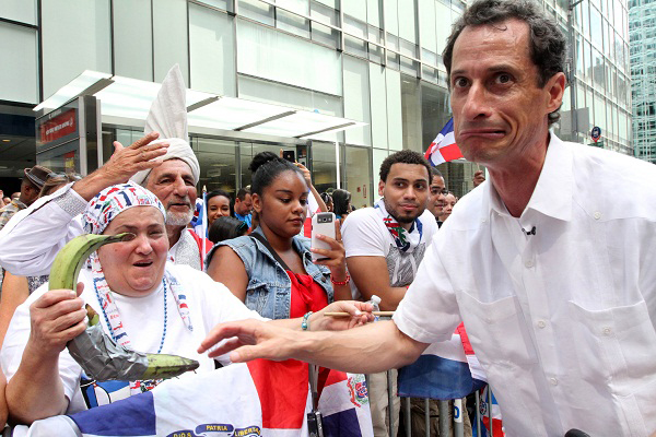 Anthony Weiner, running in the New York Mayors race, right, reacts after sharing a moment with a spectator and her plantains, left, as he takes part in the Dominican Day Parade on New York's Avenue of the Americas Sunday Aug. 11, 2013. (Photo by Tina...
