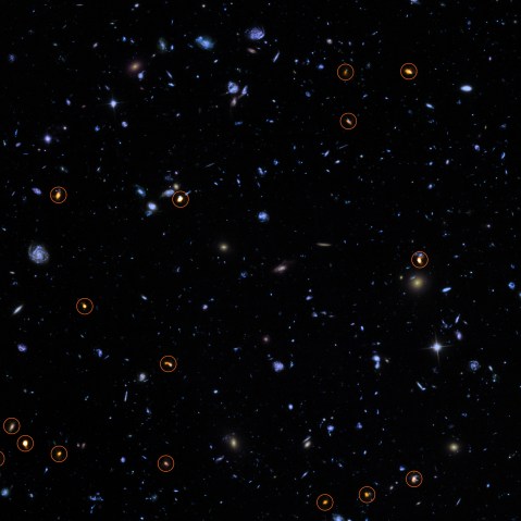 This image combines a background picture taken by the NASA/ESA Hubble Space Telescope (blue/green) with a new very deep ALMA view of this field (orange, marked with circles).
