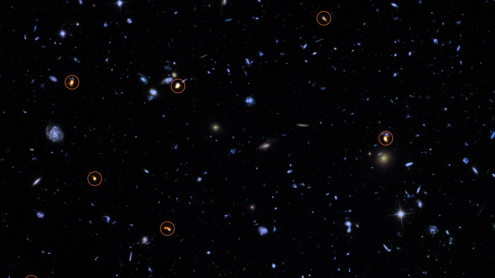 This image combines a background picture taken by the NASA/ESA Hubble Space Telescope (blue/green) with a new very deep ALMA view of this field (orange, marked with circles).