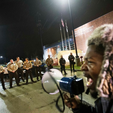 Protester Derrick Robinson shouts through a bullhorn at police officers standing guard during a demonstration outside the Ferguson Police Department on Nov. 23, 2014, in Ferguson, Mo. (David Goldman/AP)
