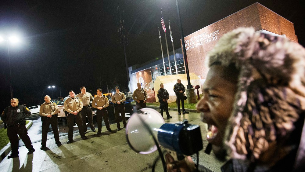 Protester Derrick Robinson shouts through a bullhorn at police officers standing guard during a demonstration outside the Ferguson Police Department on Nov. 23, 2014, in Ferguson, Mo. (David Goldman/AP)