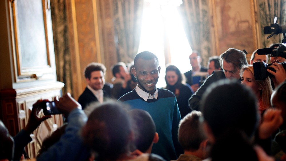 Lassana Bathily, center, talks with children prior to speeches from U.S. Secretary of State John Kerry and Paris' mayor Anne Hidalgo, at the Paris' city hall, on Jan. 16, 2015. (Photo by Thibault Camus/AP)