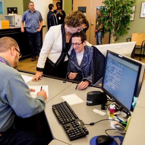 Suzanne Bryant, left, and Sarah Goodfreind hug as recording specialist Michael Mitchell for the Travis county clerk's office records the final paper work of their marriage certificate. (Photo by Ricardo B. Brazziell/Austin American-Statesman/AP)