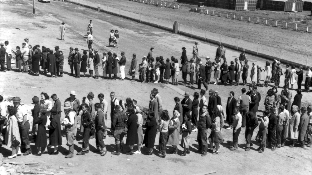 Newly arrived Japanese evacuees line up outside a mess hall at the Tanforan Assembly Center, in San Bruno, Ca., April 29, 1942. (Photo by Dorothea Lange/Interim Archives/Getty)