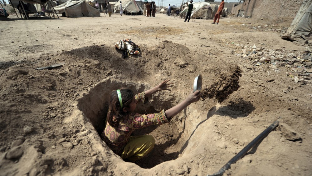 A Pakistani child digs a hole to be used as a toilet for her family at a slum in Multan on March 13, 2012. (Photo by Bay Ismoyo/AFP/Getty)