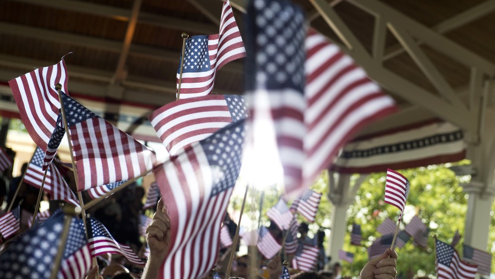 People wave American flags at an event. (Photo by Saul Loeb/AFP/Getty)