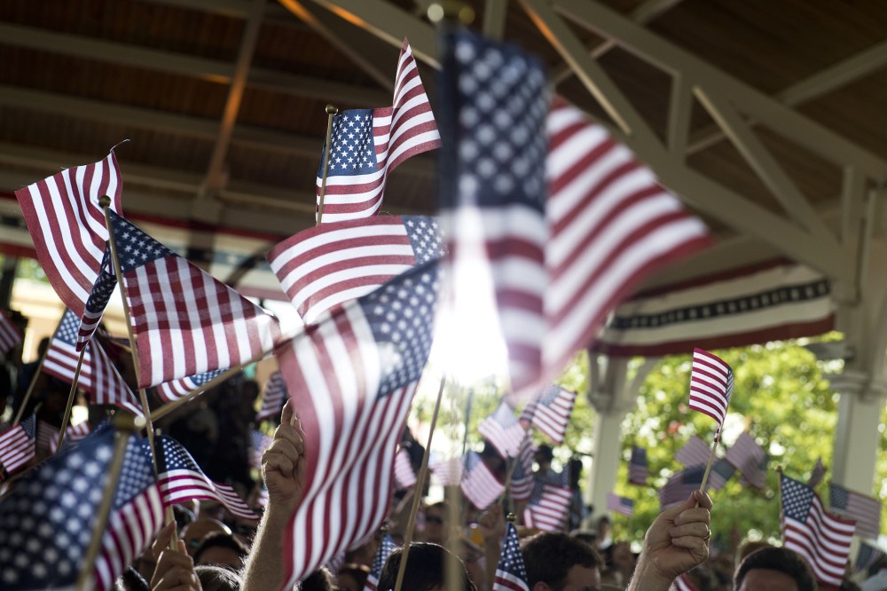 People wave American flags at an event. (Photo by Saul Loeb/AFP/Getty)