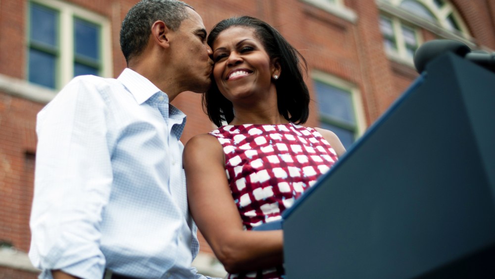 President Barack Obama (L) kisses First Lady Michelle Obama (R) as they arrive to deliver remarks during a campaign event in Dubuque, Iowa, on Aug. 15, 2012, during his three-day campaign bus tour across the state. (Photo by Jim Watson/AFP/Getty)