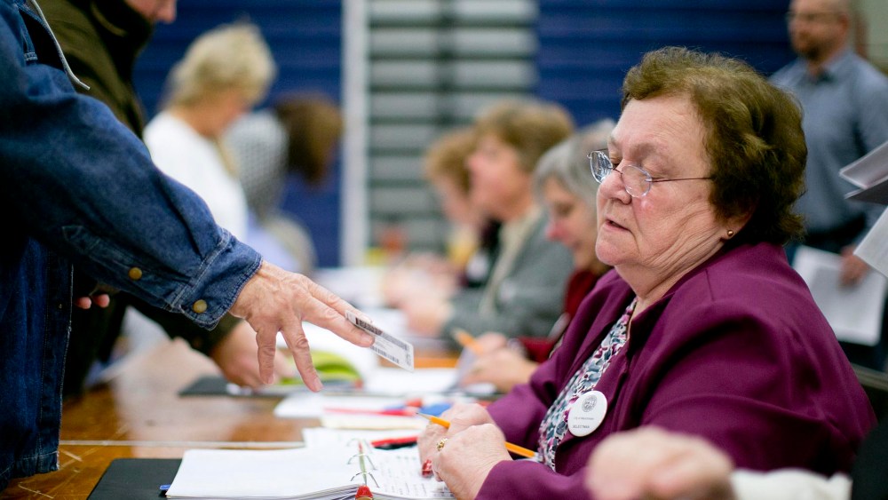 Norma Boyce checks voter identification at a polling station in Manchester, N.H., Nov. 6, 2012. (Photo by Andrew Harrer/Bloomberg/Getty)