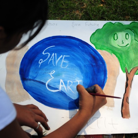 An Indian child paints during an awareness event organized by the Aakalpan Artist Society commemorating Earth Day in Allahabad on April 22, 2013.