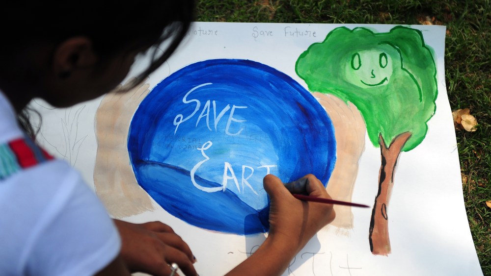An Indian child paints during an awareness event organized by the Aakalpan Artist Society commemorating Earth Day in Allahabad on April 22, 2013.