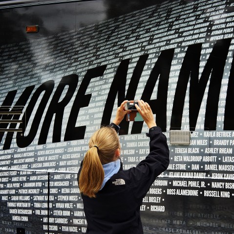 Lindsay Knauf takes a picture of a bus bearing some of the over 6,000 names of people killed by gun violence since the massacre in Newtown, six months after the massacre at Sandy Hook Elementary School on June 14, 2013. (Photo by Spencer Platt/Getty)