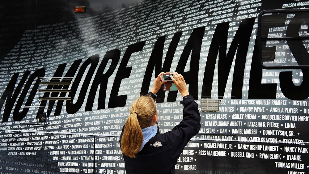 Lindsay Knauf takes a picture of a bus bearing some of the over 6,000 names of people killed by gun violence since the massacre in Newtown, six months after the massacre at Sandy Hook Elementary School on June 14, 2013. (Photo by Spencer Platt/Getty)