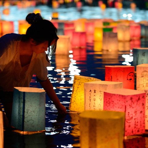 A woman floats paper lanterns lit in remembrance for victims of the 1945 atomic bombing of Hiroshima on the Motoyasu River at the Peace Memorial Park in Hiroshima, western Japan, on Aug. 6, 2013. (Photo by Toru Yamanaka/AFP/Getty)