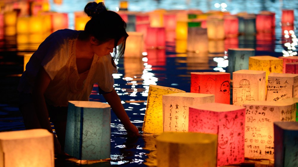 A woman floats paper lanterns lit in remembrance for victims of the 1945 atomic bombing of Hiroshima on the Motoyasu River at the Peace Memorial Park in Hiroshima, western Japan, on Aug. 6, 2013. (Photo by Toru Yamanaka/AFP/Getty)