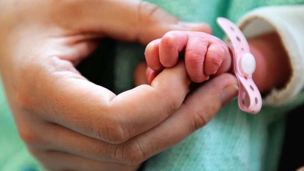 A new born baby takes the finger of his mother after the delivery. (Photo by Philippe Huguen/AFP/Getty)